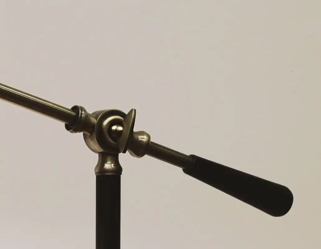 Close view of the brass knuckle where the lamp arm meets the post, with the black counterweight handle