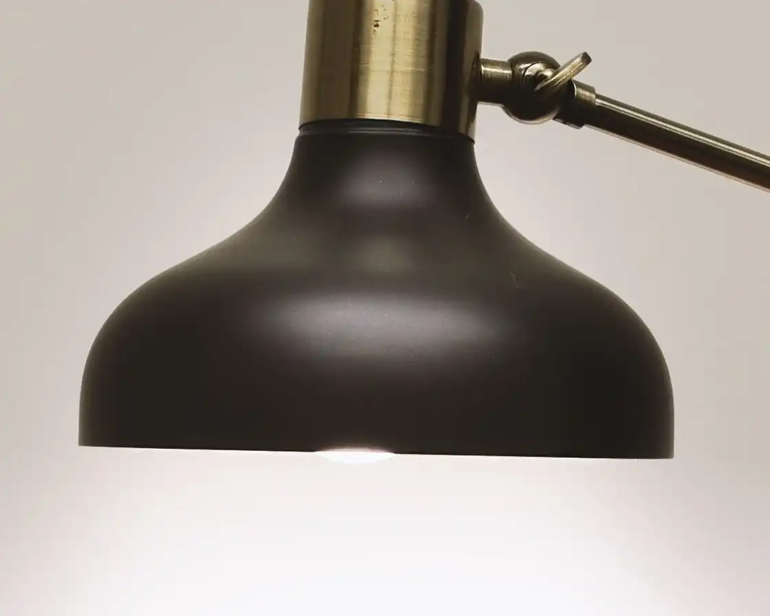 The domed graphite shade and brass cap from below, with warm light falling from the opening