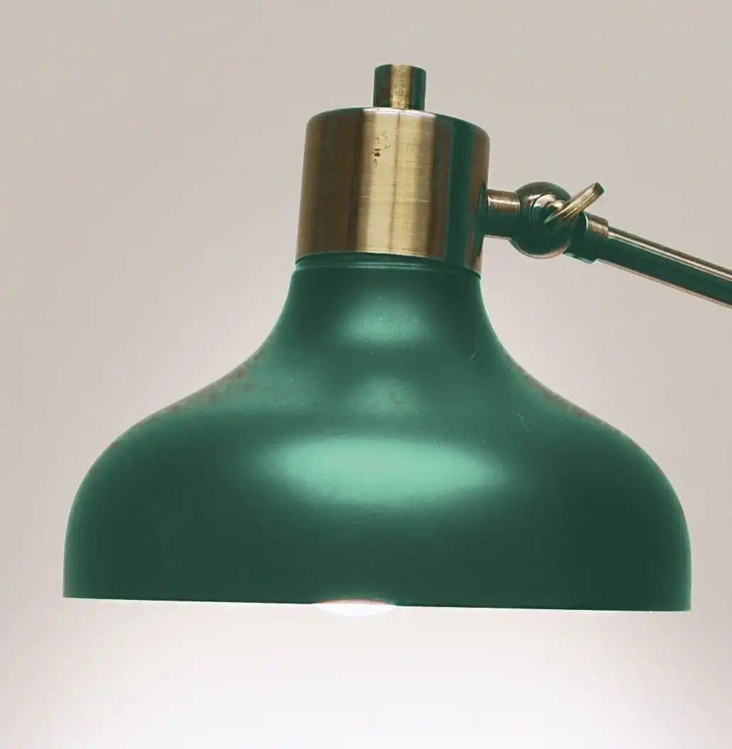 A domed fern green lamp shade with a brass cap