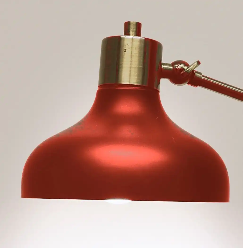 A domed oxide red lamp shade with a brass cap