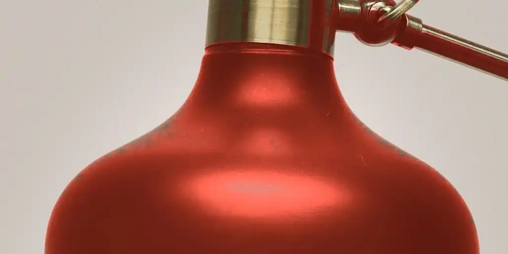 A domed oxide red lamp shade with a brass cap